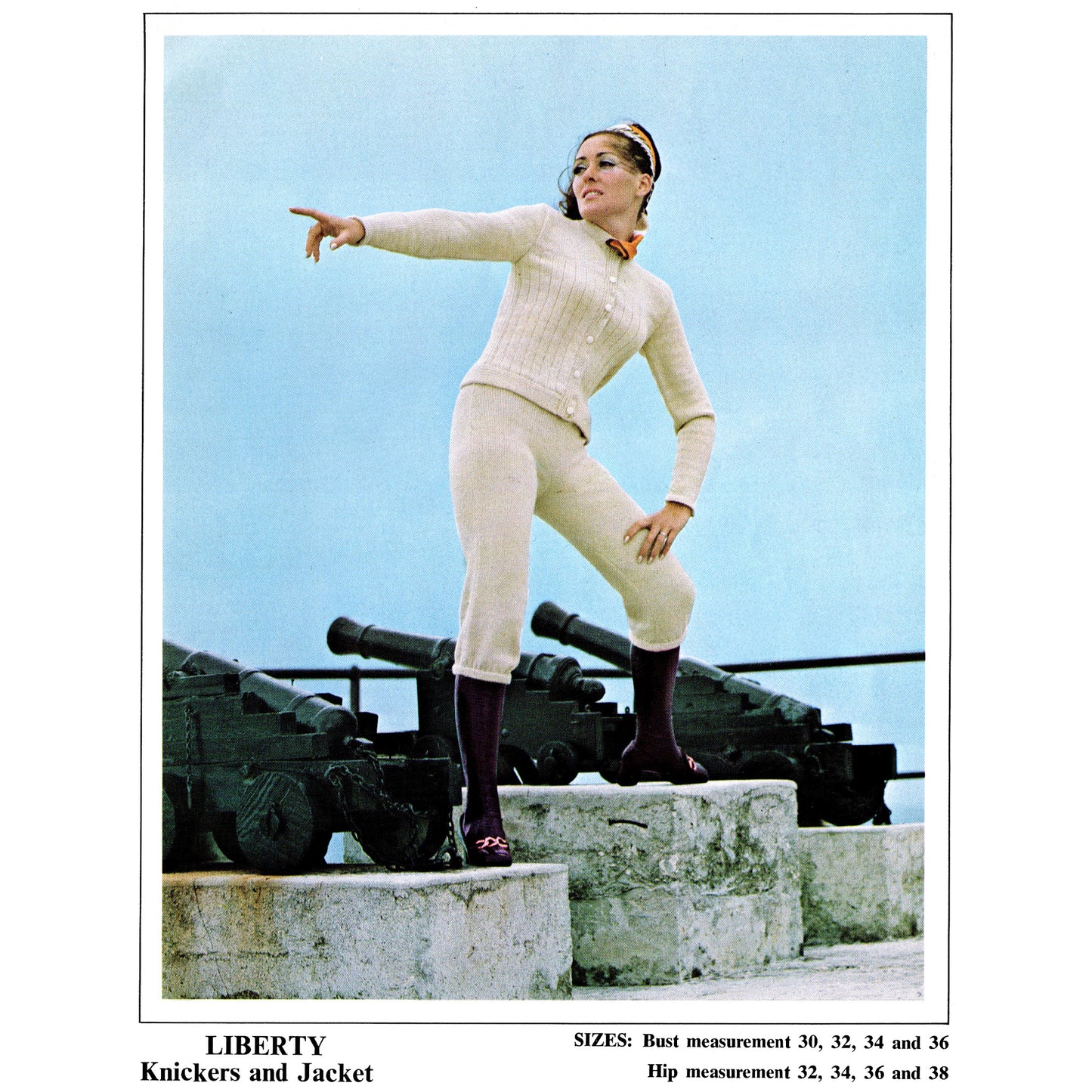 Woman in a white outfit standing on a set of cannons with a blue sky background