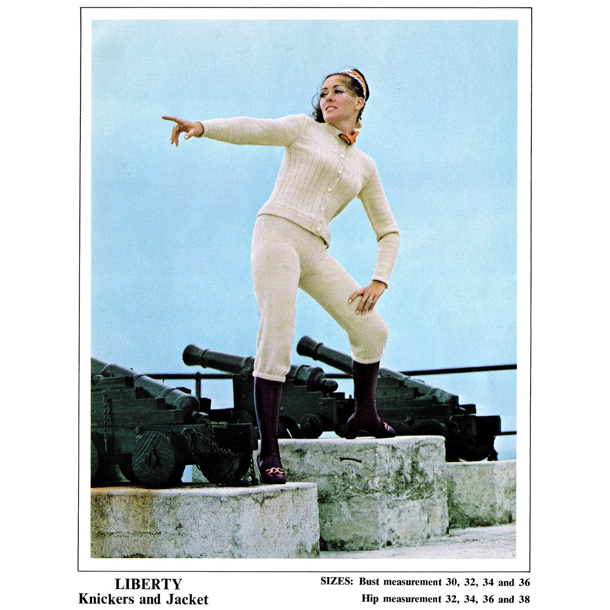 Woman in a white outfit standing on a set of cannons with a blue sky background