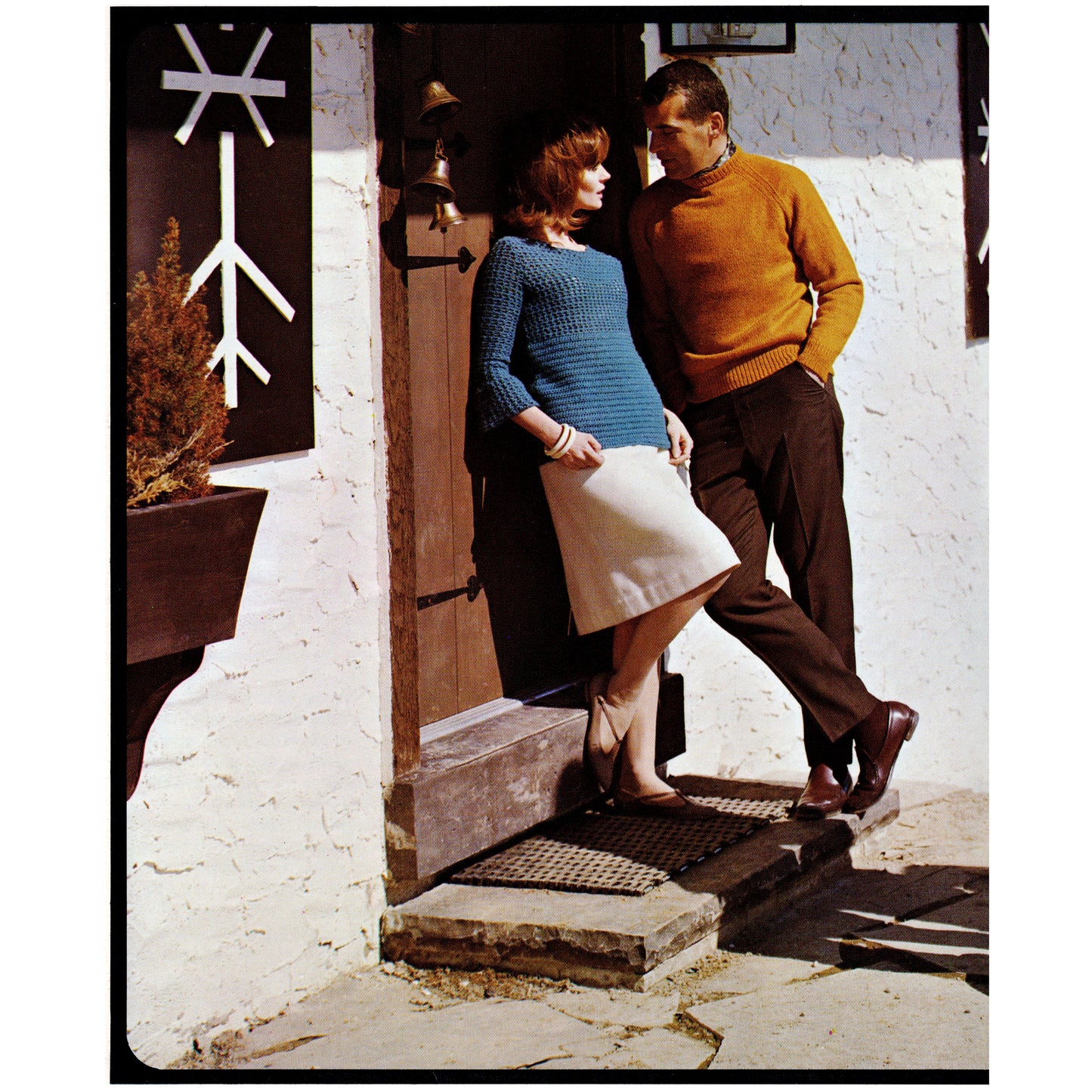 Man and woman standing on a doorstep with a white wall and door in the background