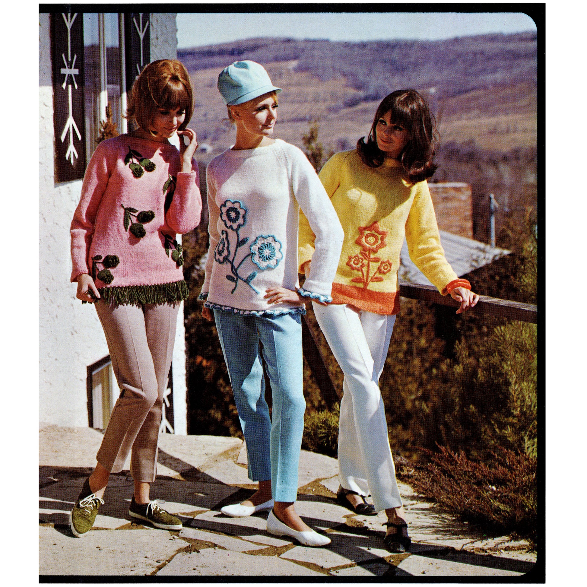 Three women in colorful embroidered sweaters and pants standing outdoors with a scenic background.